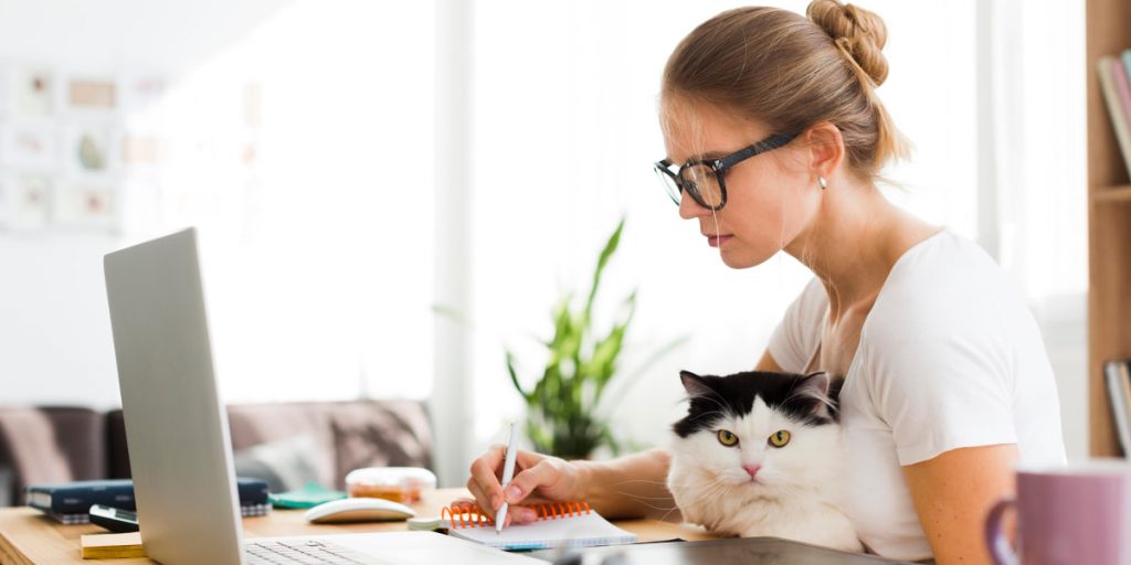 woman is making notes and holding a cat