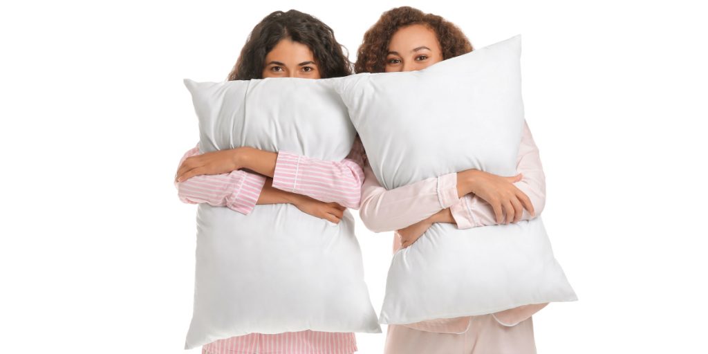 girls hiding behind feather pillows