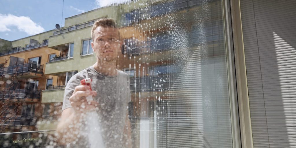 man is spraying windows with windows cleaner