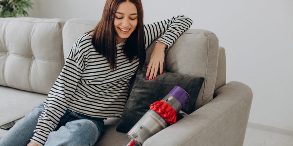 woman is looking at the vacuum cleaner on the couch