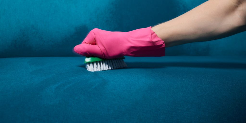 wiping sofa's surface with a brush