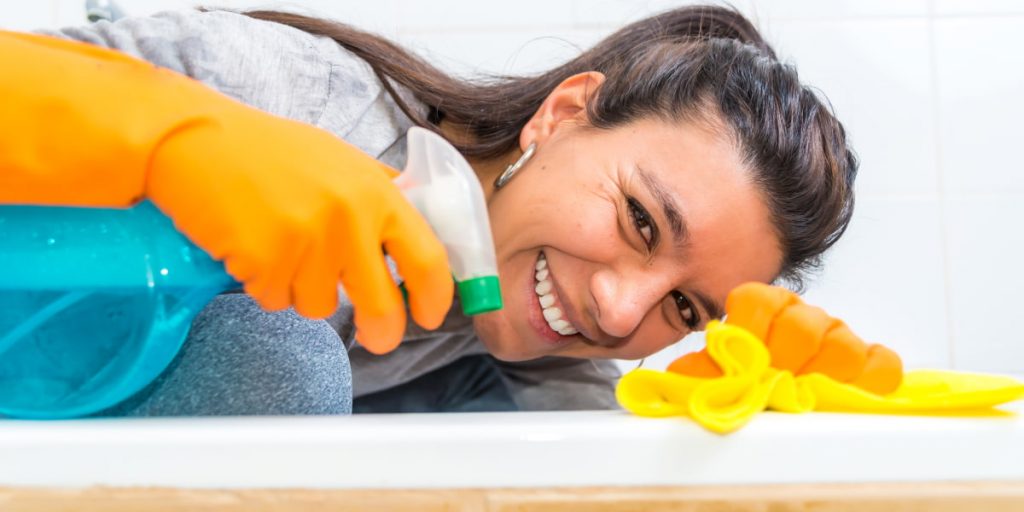 woman use spray to prolong a cleaned bathtub